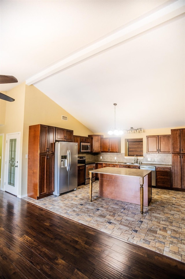 kitchen with decorative light fixtures, lofted ceiling with beams, stainless steel appliances, and light wood-type flooring