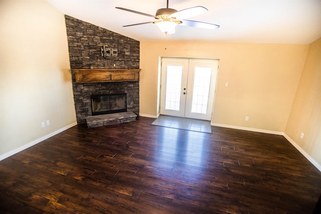 unfurnished living room with french doors, dark wood-type flooring, a stone fireplace, vaulted ceiling, and ceiling fan