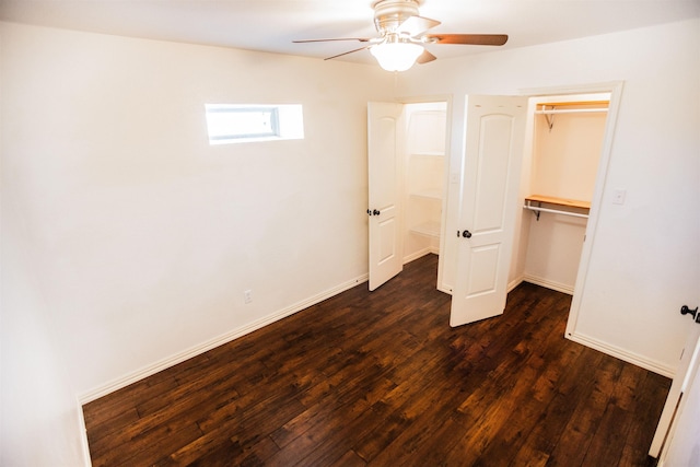 unfurnished bedroom with a spacious closet, dark wood-type flooring, ceiling fan, and a closet