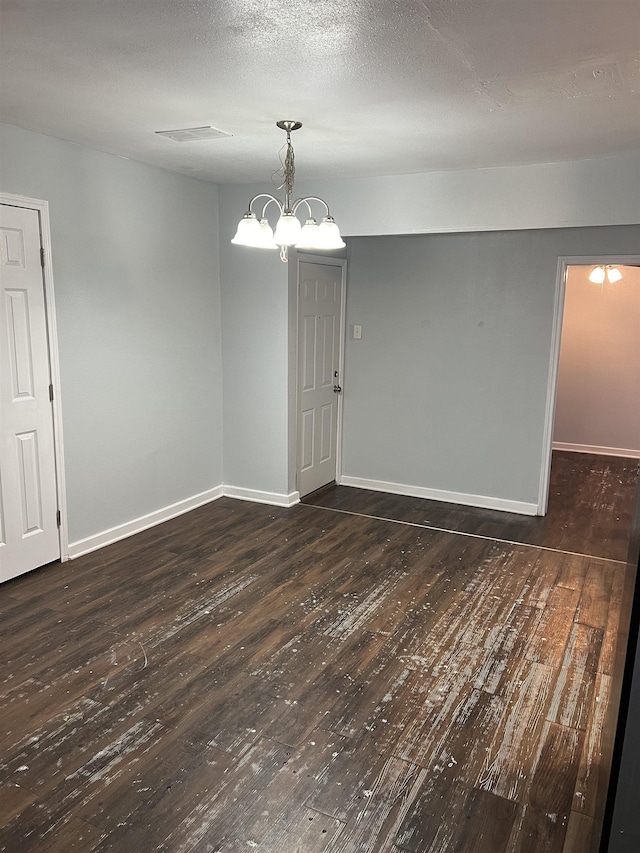 unfurnished room featuring dark hardwood / wood-style flooring and an inviting chandelier