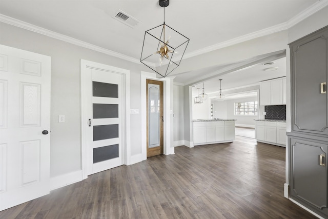 interior space featuring crown molding, a chandelier, visible vents, baseboards, and dark wood-style floors