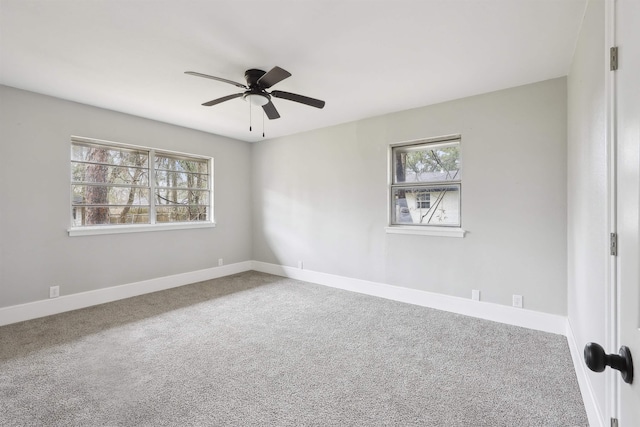 carpeted spare room with a ceiling fan and baseboards