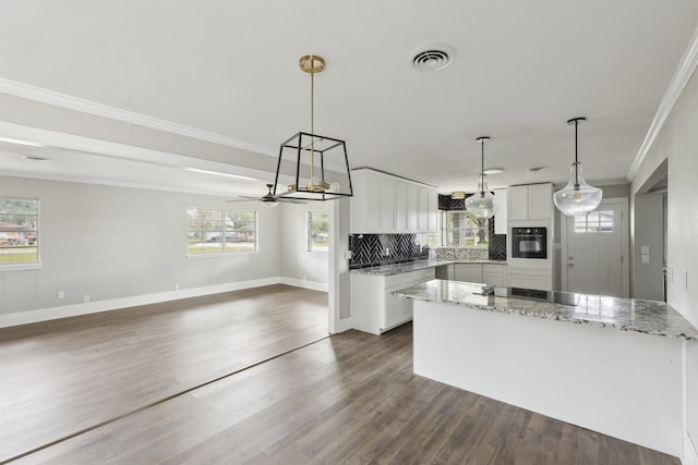 kitchen with crown molding, tasteful backsplash, oven, white cabinetry, and visible vents