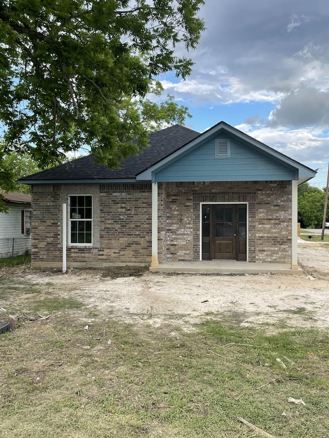 back of house with brick siding and roof with shingles