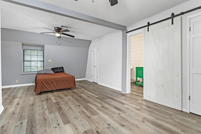 134 Sherwood Trl, Silsbee, TX 77656 - unfurnished living room featuring ceiling fan, a textured ceiling, wood finished floors, a barn door, and baseboards