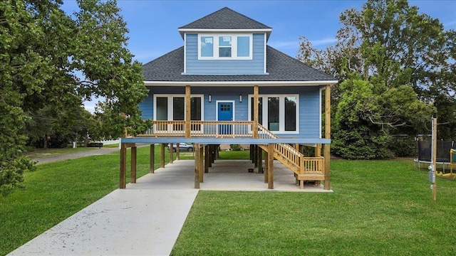 back of house with covered porch, a yard, and a trampoline