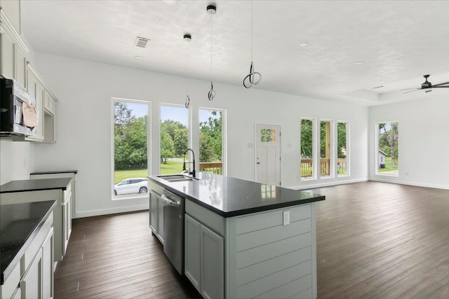 kitchen with ceiling fan, sink, stainless steel appliances, decorative light fixtures, and a kitchen island with sink