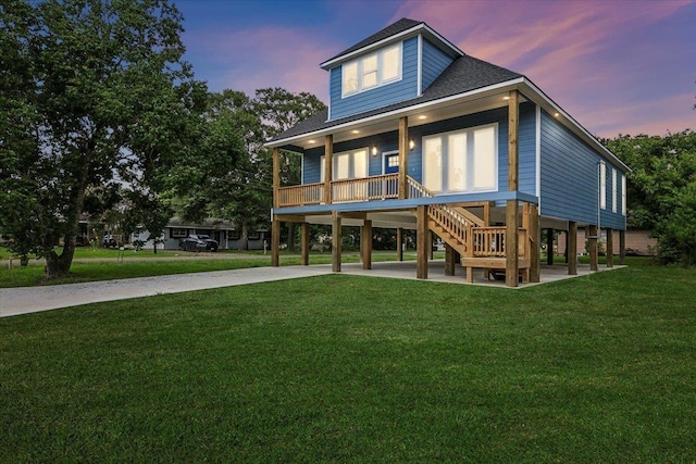 back house at dusk featuring a porch, a yard, and a carport