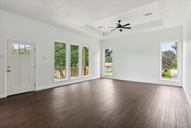 unfurnished living room with dark hardwood / wood-style floors, ceiling fan, and a raised ceiling