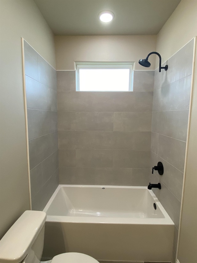 bathroom featuring tiled shower / bath combo and toilet