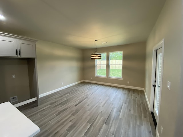 unfurnished dining area with light hardwood / wood-style floors and an inviting chandelier