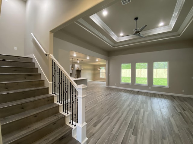 interior space with hardwood / wood-style flooring, ceiling fan, a raised ceiling, and crown molding