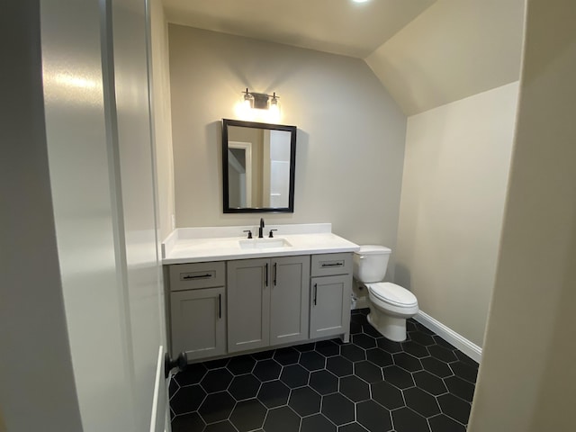 bathroom with toilet, tile patterned floors, vanity, and vaulted ceiling