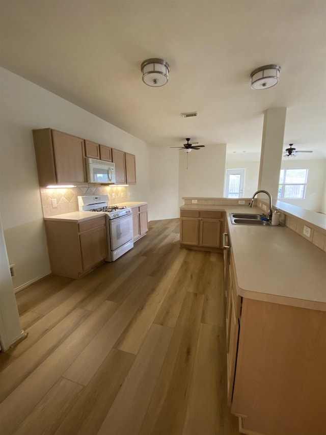 kitchen with decorative backsplash, ceiling fan, a sink, light wood finished floors, and white appliances