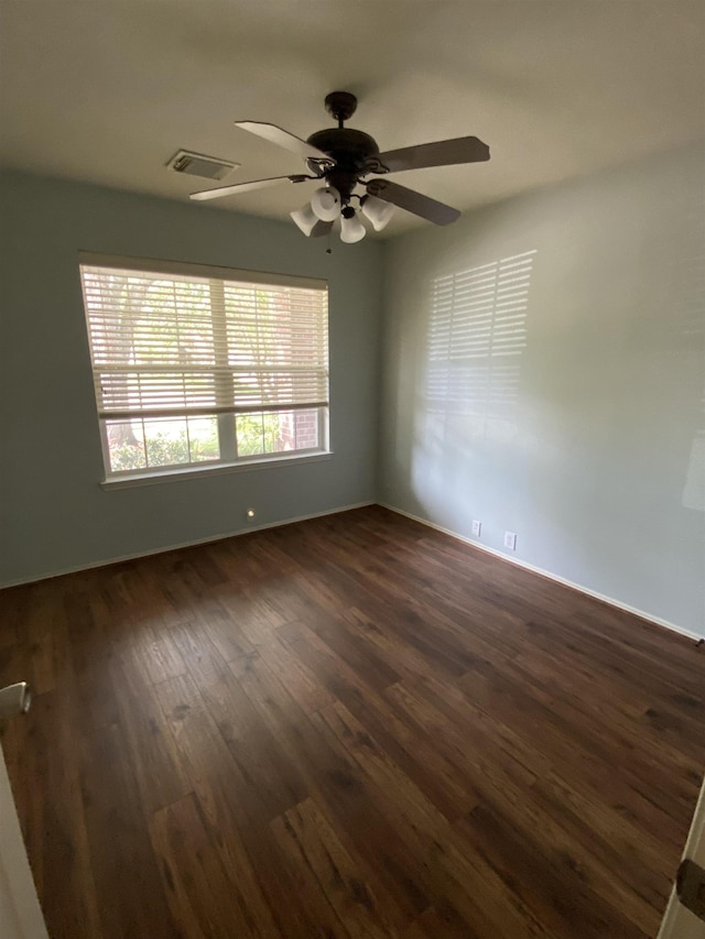 empty room featuring baseboards, a ceiling fan, dark wood-style flooring, and visible vents