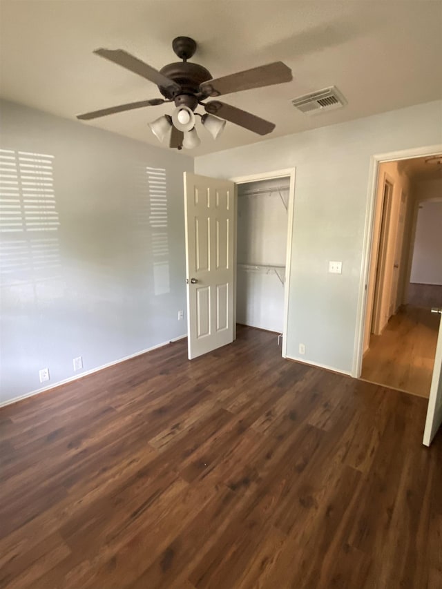 unfurnished bedroom with a ceiling fan, baseboards, dark wood-type flooring, visible vents, and a closet