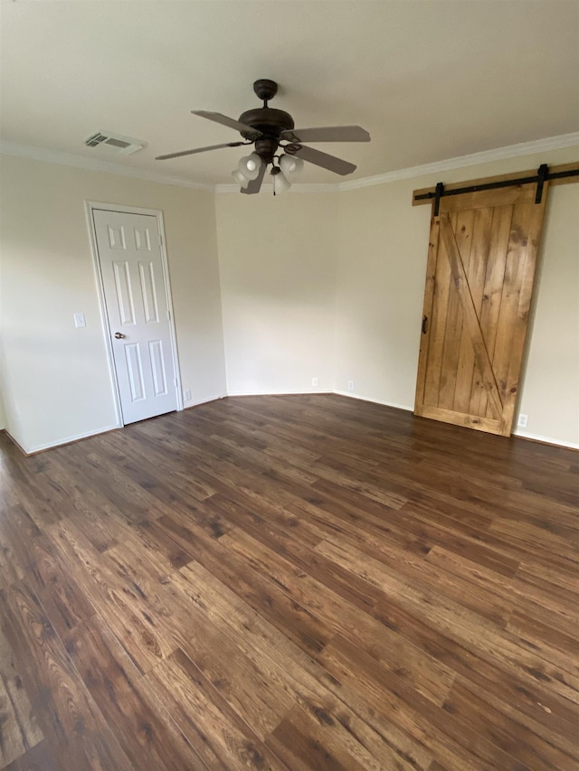 unfurnished room with crown molding, a barn door, and dark wood-style flooring