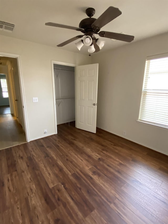 unfurnished bedroom with ceiling fan, visible vents, baseboards, a closet, and dark wood-style floors