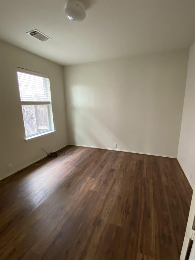 unfurnished room with dark wood-style flooring and visible vents