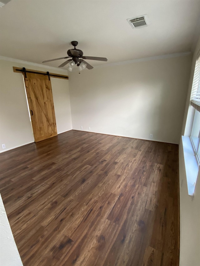 empty room with visible vents, a barn door, crown molding, and ceiling fan