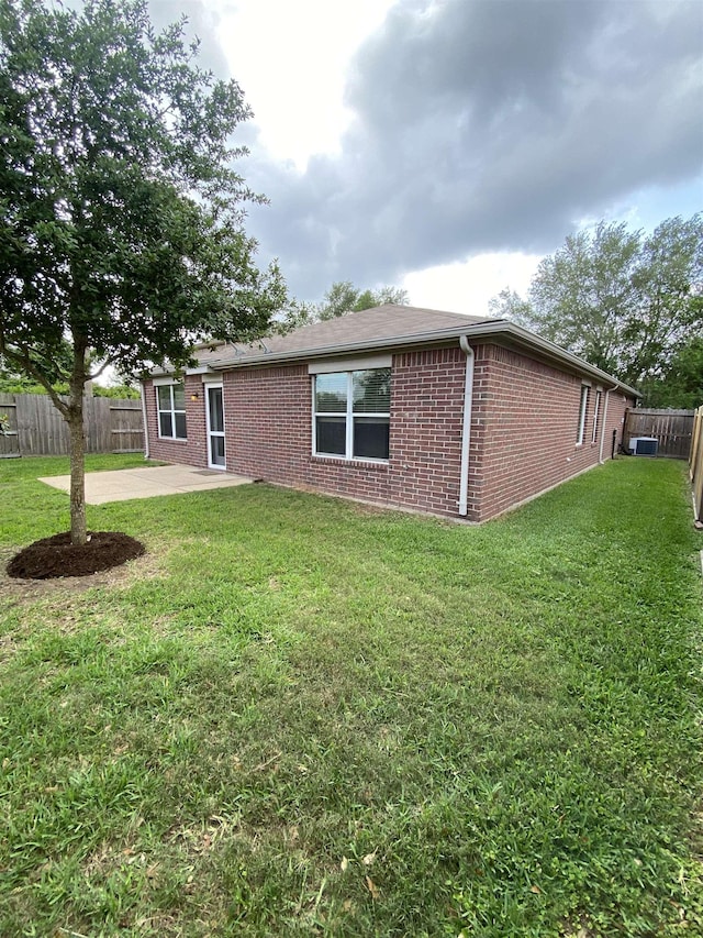 back of house featuring a fenced backyard, a patio, a yard, and brick siding