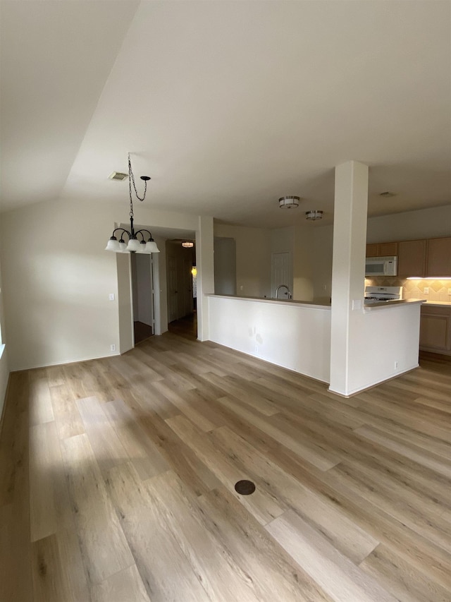 unfurnished living room featuring a chandelier, visible vents, light wood-style flooring, and lofted ceiling