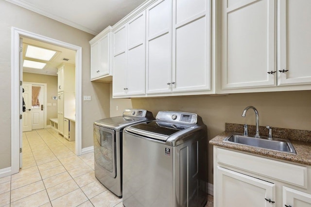 washroom with light tile patterned flooring, washing machine and clothes dryer, sink, cabinets, and ornamental molding