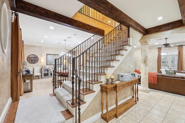 staircase with tile patterned flooring, beam ceiling, ceiling fan with notable chandelier, and decorative columns