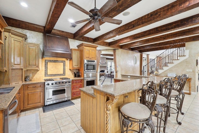 kitchen featuring a kitchen breakfast bar, ceiling fan, stainless steel appliances, custom range hood, and beam ceiling