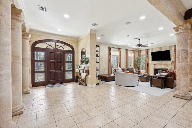 foyer entrance featuring light tile patterned flooring, ceiling fan, crown molding, and decorative columns