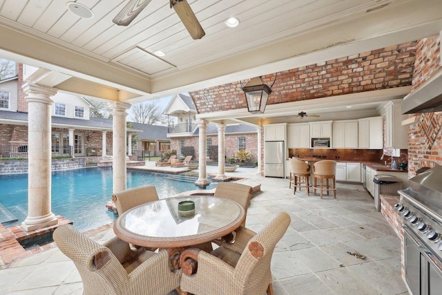 view of pool with decorative columns, sink, and ceiling fan