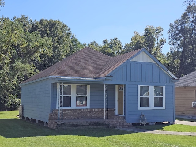 view of front of home with a front yard, board and batten siding, a porch, and roof with shingles