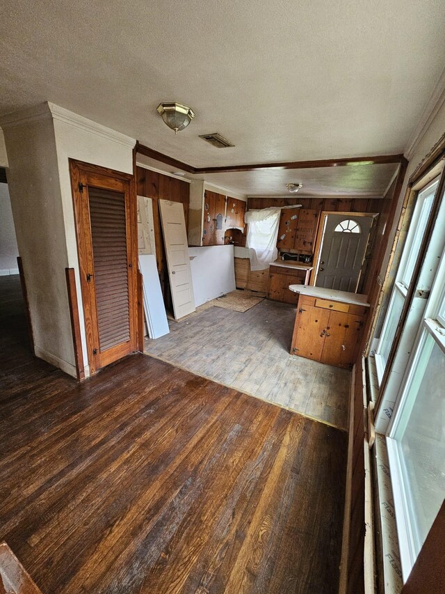 kitchen with ornamental molding, hardwood / wood-style flooring, light countertops, a peninsula, and a textured ceiling