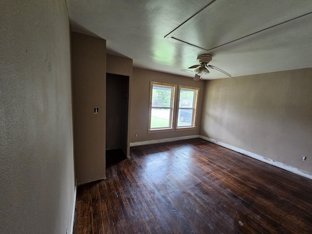 empty room featuring dark wood finished floors, ceiling fan, and baseboards