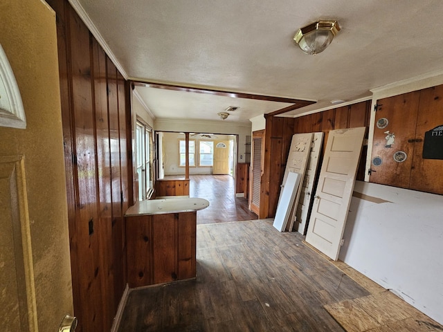 kitchen with ornamental molding, wood finished floors, and wood walls