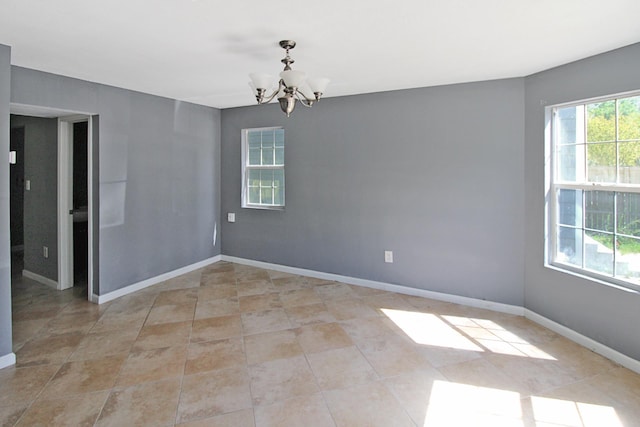 empty room featuring light tile patterned floors, baseboards, and a notable chandelier