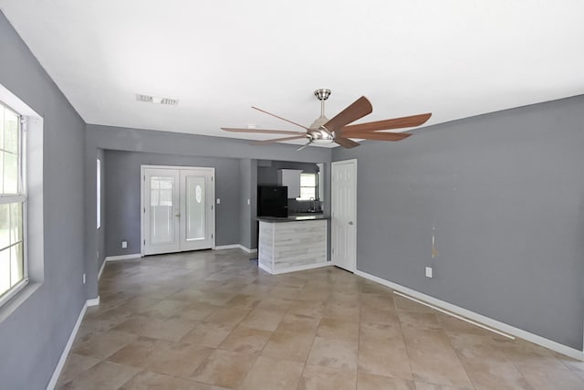 unfurnished living room with visible vents, baseboards, and ceiling fan