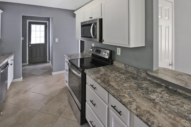kitchen featuring dark stone countertops, light tile patterned floors, white cabinets, baseboards, and appliances with stainless steel finishes