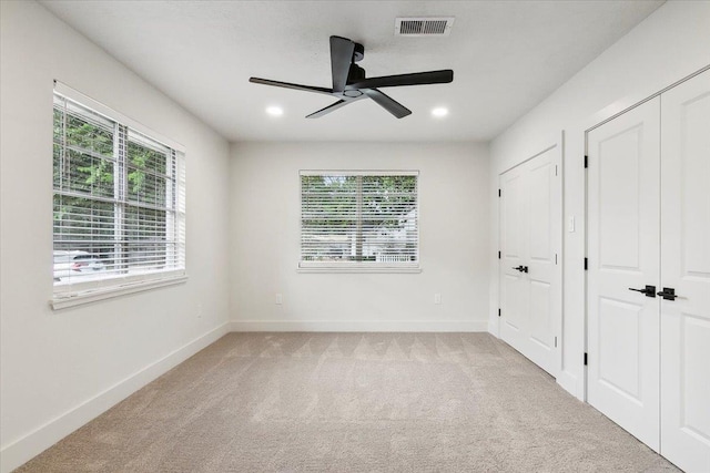 unfurnished bedroom with ceiling fan, light colored carpet, and multiple windows