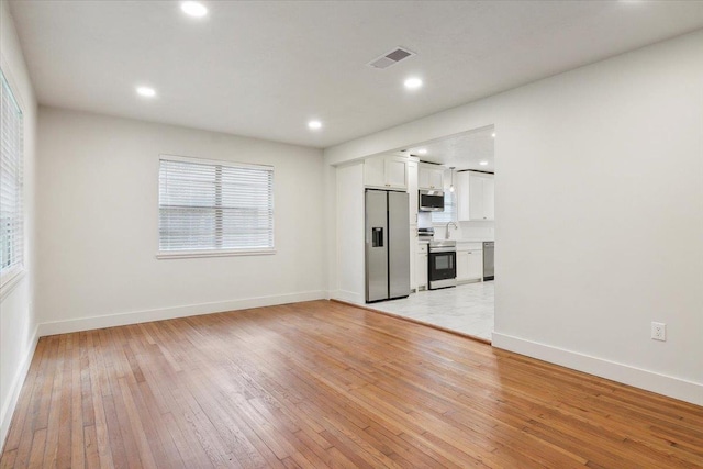 unfurnished living room featuring sink and light hardwood / wood-style flooring