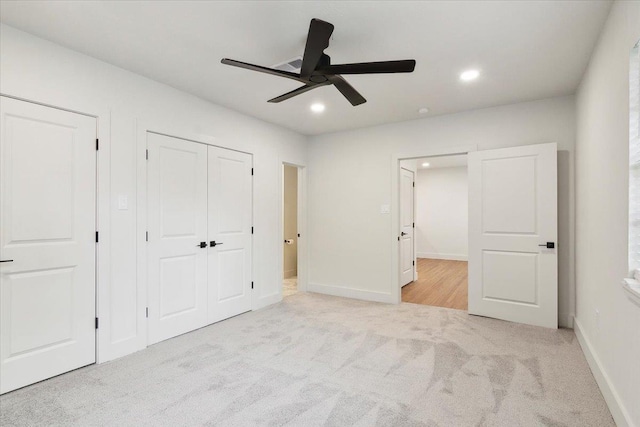 unfurnished bedroom featuring ceiling fan, light carpet, and multiple closets