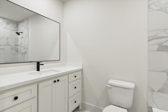 bathroom featuring tiled shower, vanity, and toilet