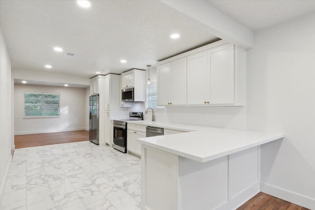 kitchen featuring white cabinets, decorative light fixtures, stainless steel appliances, and kitchen peninsula