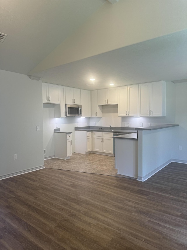 kitchen featuring dark hardwood / wood-style flooring, white cabinetry, vaulted ceiling, and sink