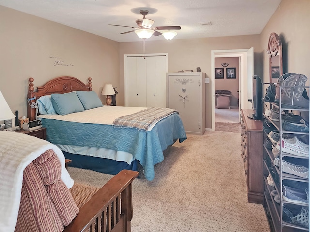 bedroom with a closet, a ceiling fan, light colored carpet, and visible vents
