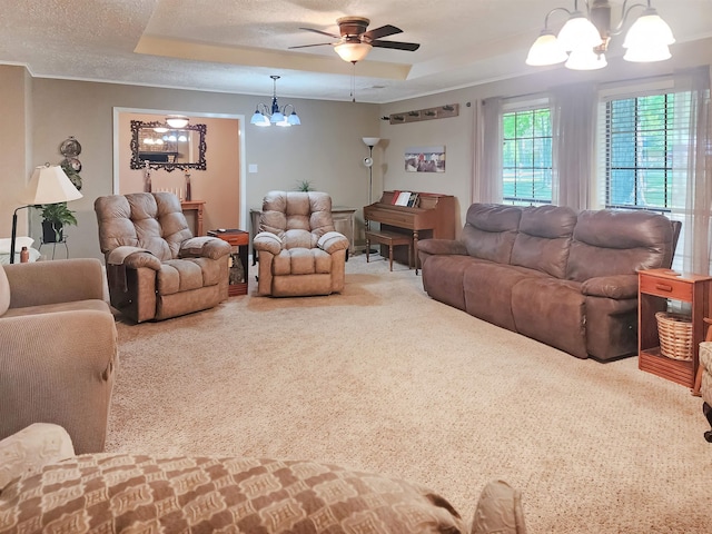 living area featuring a raised ceiling, ceiling fan with notable chandelier, and carpet