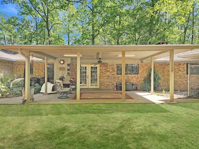 rear view of house with a yard, french doors, brick siding, and a patio area