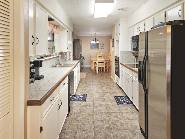 kitchen featuring tile counters, white cabinetry, backsplash, black appliances, and a sink