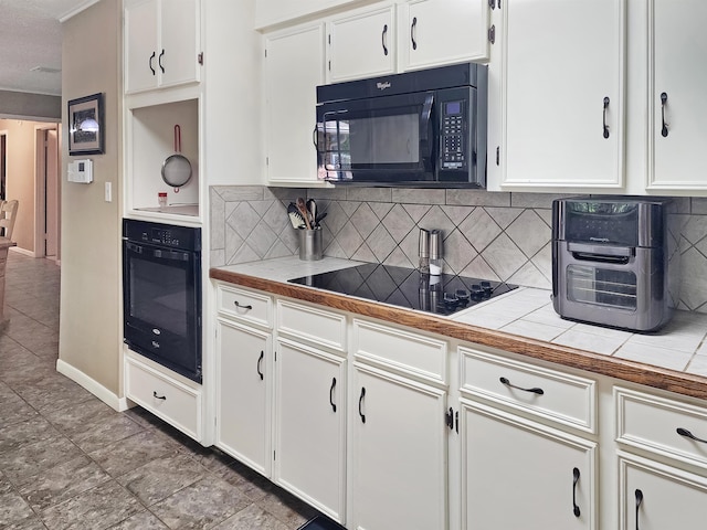 kitchen with tile counters, white cabinets, and black appliances