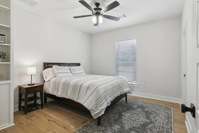 bedroom with visible vents, light wood-style flooring, a ceiling fan, and baseboards